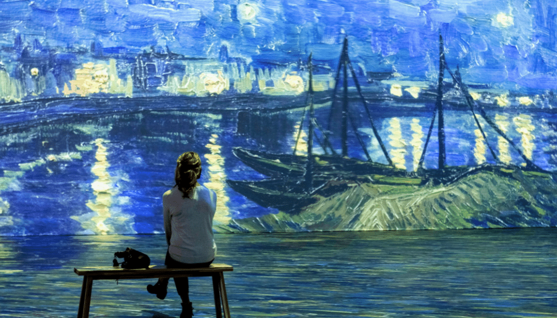 A person sitting on a bench at the Beyond Van Gogh exhibit.